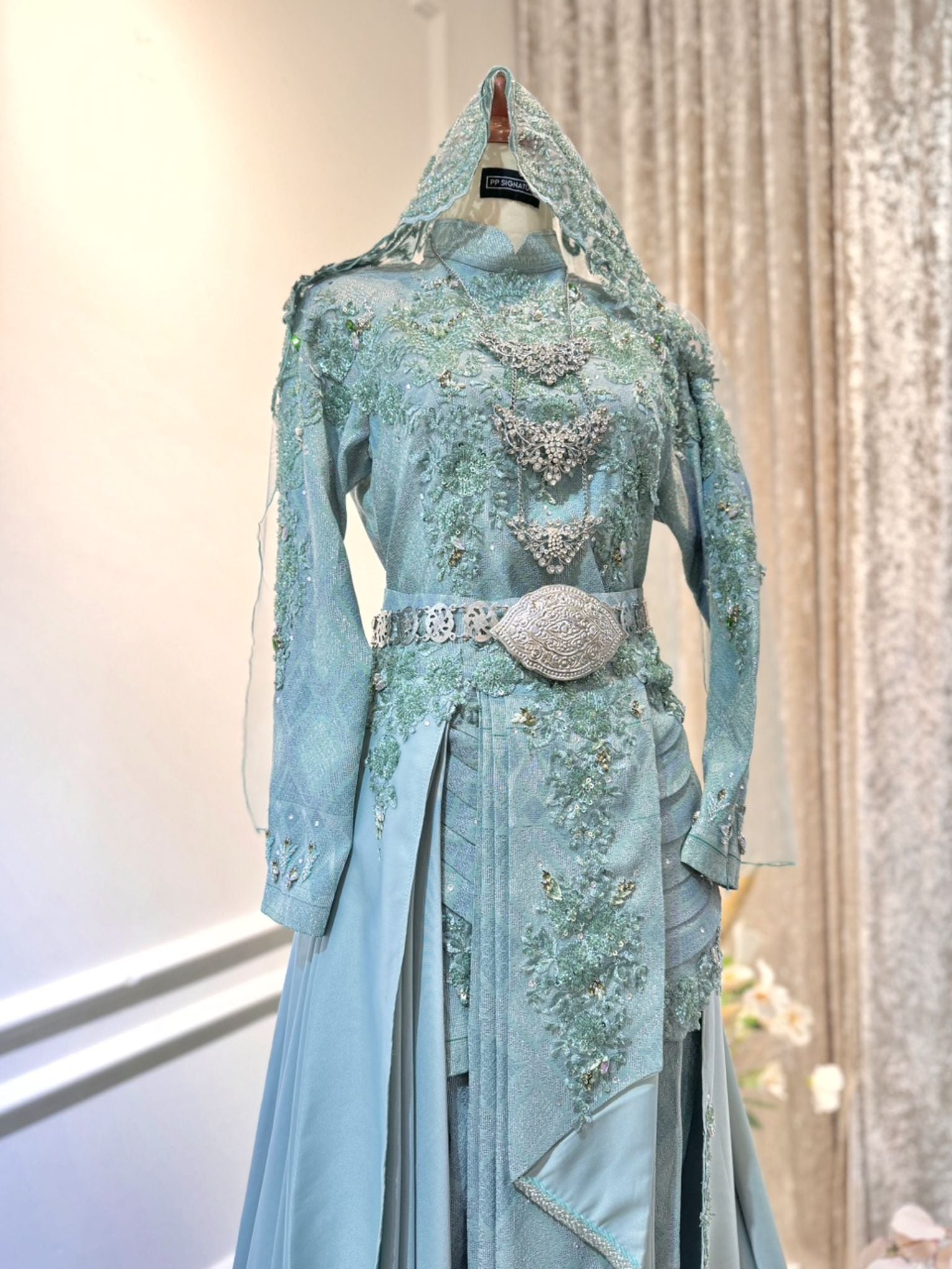 Our Sage Green Songket Dress features a classic two-piece design with gracefully tailored pants, adorned with intricate Songket 3D detailing. The detachable trail adds a touch of regal charm, allowing you to customize your look with ease. Embrace tradition with a modern twist and captivate everyone with your impeccable style.