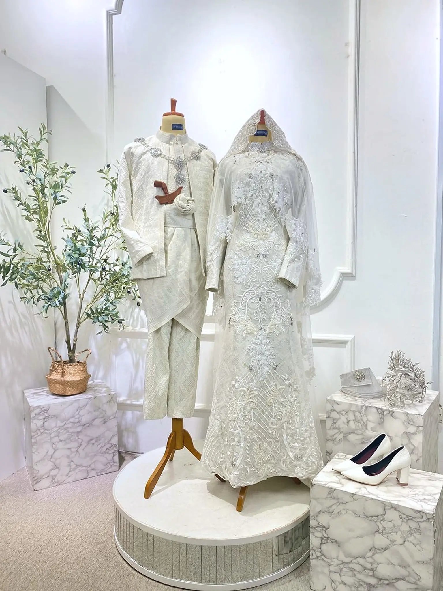 White embroidered traditional outfits on mannequins with a decorative background-Malay bride and groom in Off White Baju Pengantin Almaz set from PP Signature Bridal for Sewa Baju Sanding