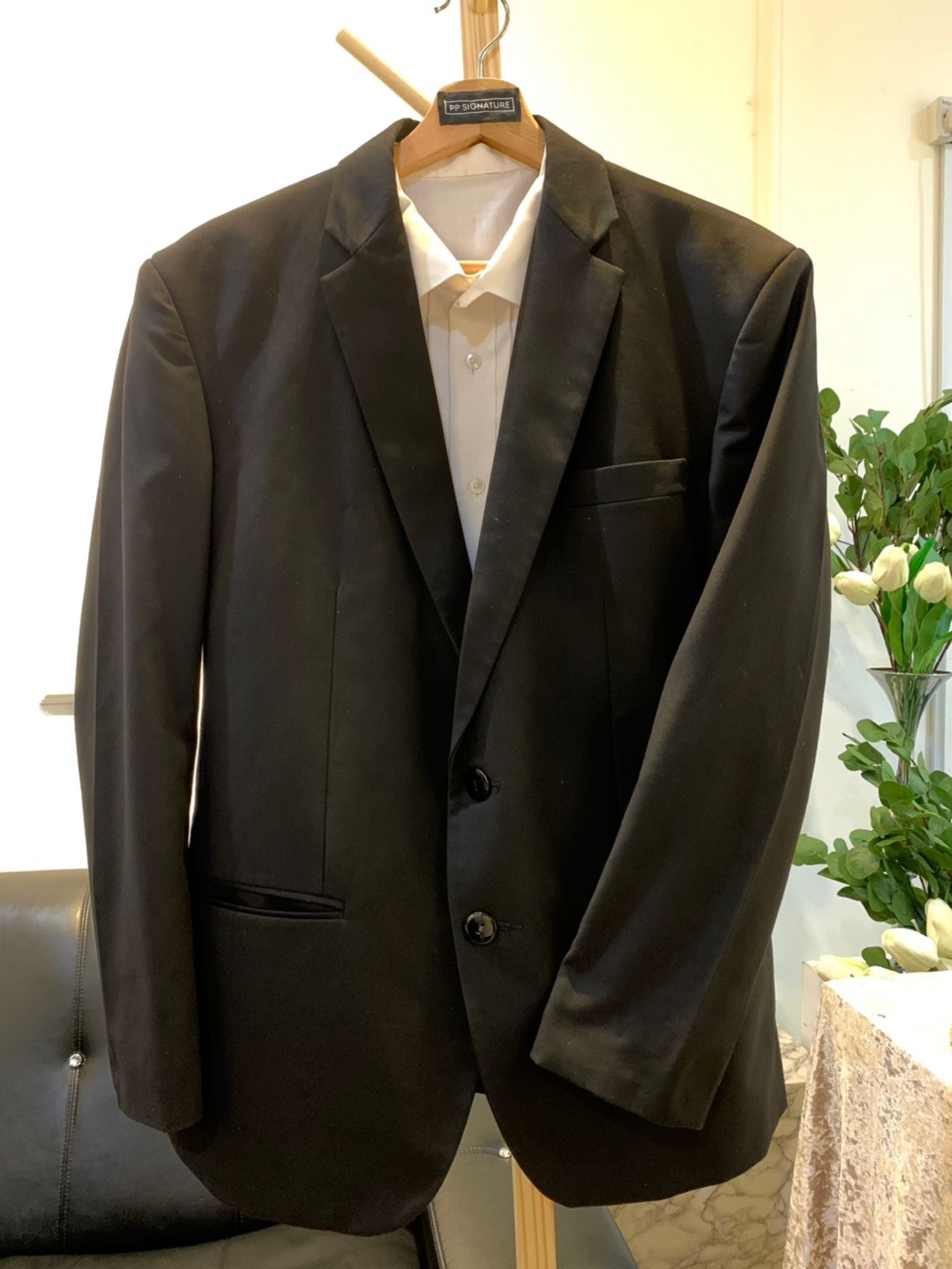 A close-up image of a black wedding suit with a notch lapel. The suit is made from high-quality wool fabric and is fully lined for a comfortable fit. It is the perfect choice for a formal occasion, such as a wedding or black tie gala.