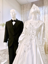 Immerse yourself in sophistication with Jasmine, a captivating ensemble tailored for both the bride and groom. The image showcases the bride's attire, crafted from luxurious Duchess fabric with delicate lace detailing, featuring a stunning Ballgown design paired with a graceful petticoat. Meanwhile, the groom radiates elegance with a choice between a classic Suit or the intricate Kot Raihan Three-Piece ensemble.