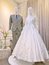 Immerse yourself in sophistication with Jasmine, a captivating ensemble tailored for both the bride and groom. The image showcases the bride's attire, crafted from luxurious Duchess fabric with delicate lace detailing, featuring a stunning Ballgown design paired with a graceful petticoat. Meanwhile, the groom radiates elegance with a choice between a classic Suit or the intricate Kot Raihan Three-Piece ensemble.