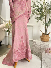 Pink embroidered dress on a mannequin with a white background and decorative elements.