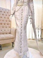 A photograph showcasing Nilam Sari's Baju Pengantin Songket in White with Silver, a blend of Thai-inspired bridal attire. The image captures the bride's ensemble, featuring a graceful Thai Dress design crafted from luxurious Songket 2D material, and the groom's attire, adorned with the intricate Kot Raihan 2pcs