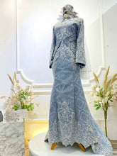 Graceful Malay wedding dress in songket fabric with intricate detailing.