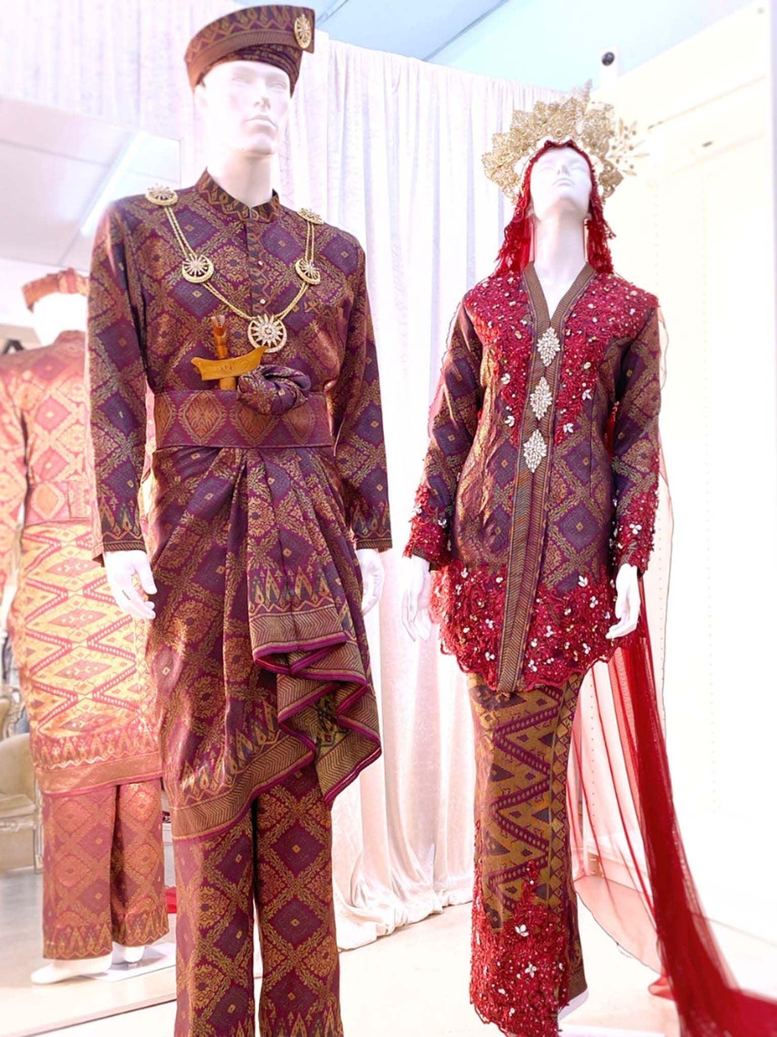 Sepasang Baju Pengantin Kebaya Songket lengkap aksesori oleh Butik Pengantin PP Signature dipakai patung Lelaki dan perempuan berwarna merah maroon untuk disewa-A pair of Kebaya songket wedding dresses complete with accessories by PP Signature Bridal Boutique worn by male and female statues in maroon for rent