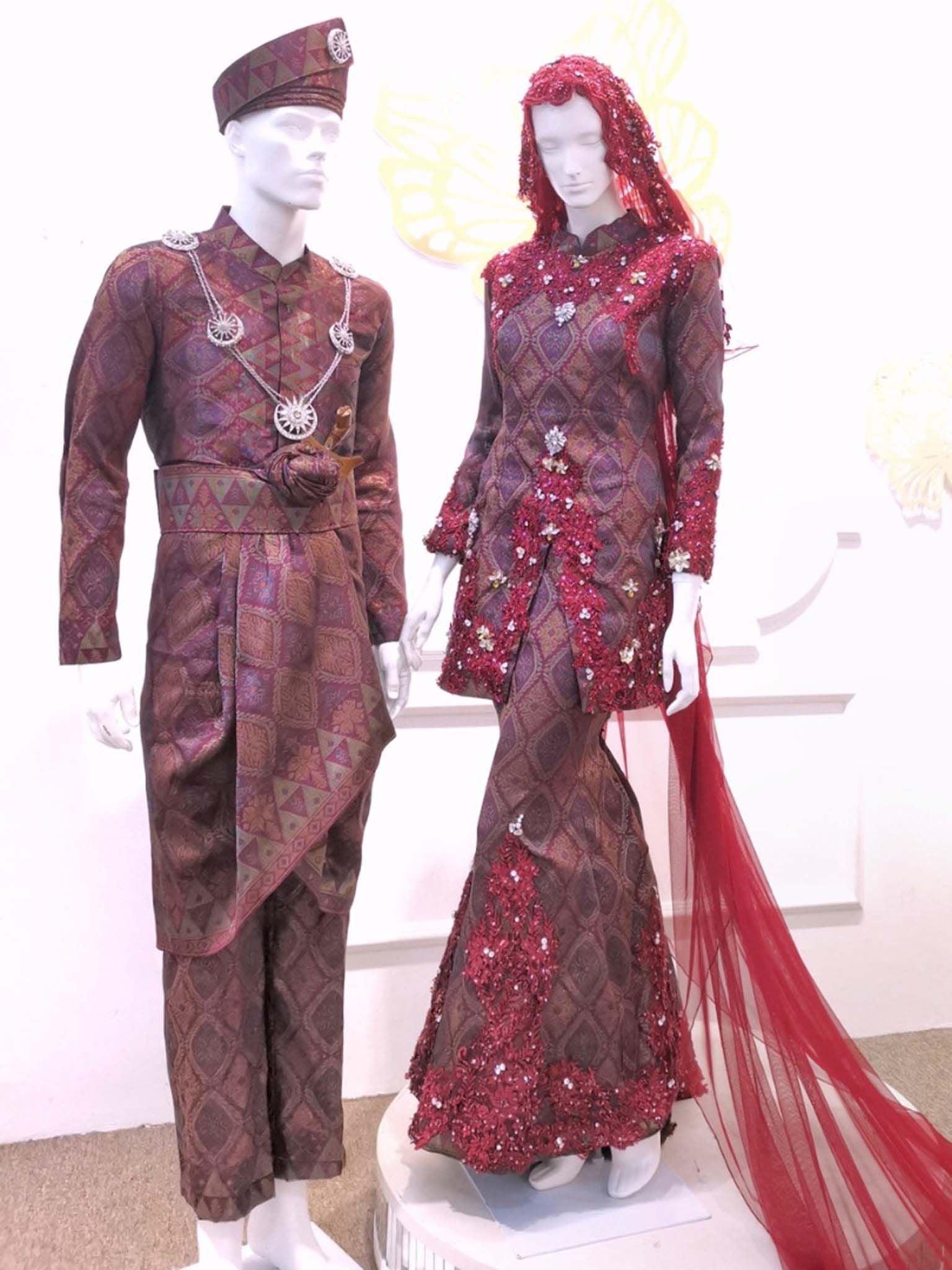 Sepasang Baju Pengantin Baju Kurung Moden Songket lengkap aksesori oleh Butik Pengantin PP Signature dipakai patung Lelaki dan perempuan berwarna merah maroon untuk disewa-A pair of Modern Kurung Songket Dress wedding dresses complete with accessories by PP Signature Bridal Boutique worn by male and female statues in maroon for rent