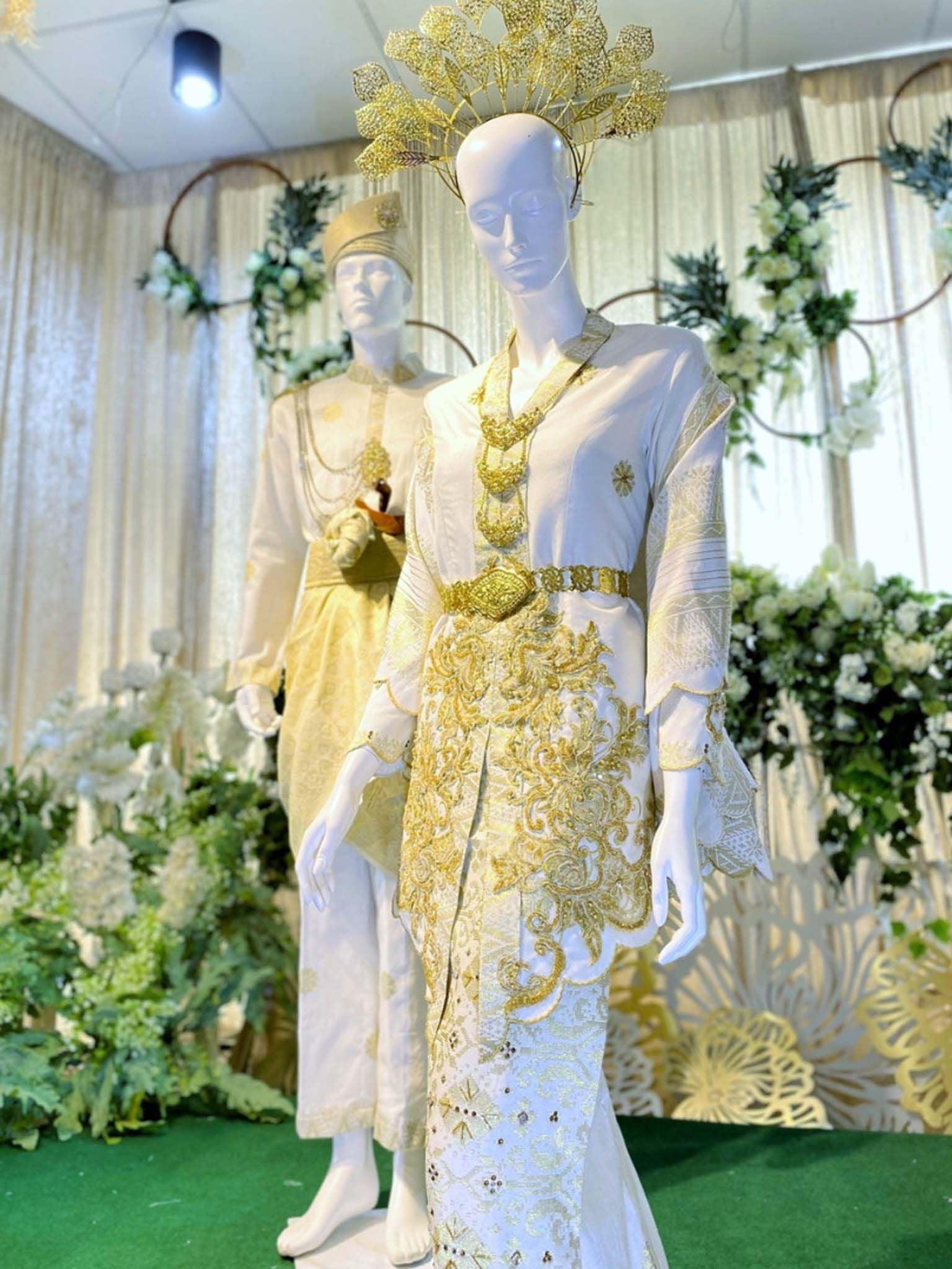 Sepasang baju pengantin, baju Kebaya songket berwarna putih dan emas yang dihias menggunakan teknik tambour dan sulaman tangan lengkap aksesori buatan Butik Pengantin PP Signature-A pair of wedding dresses, Kebaya Dress in off-white and gold complete songket embellished using tambour technique and hand embroidery complete with accessories made by PP Signature Bridal Boutique