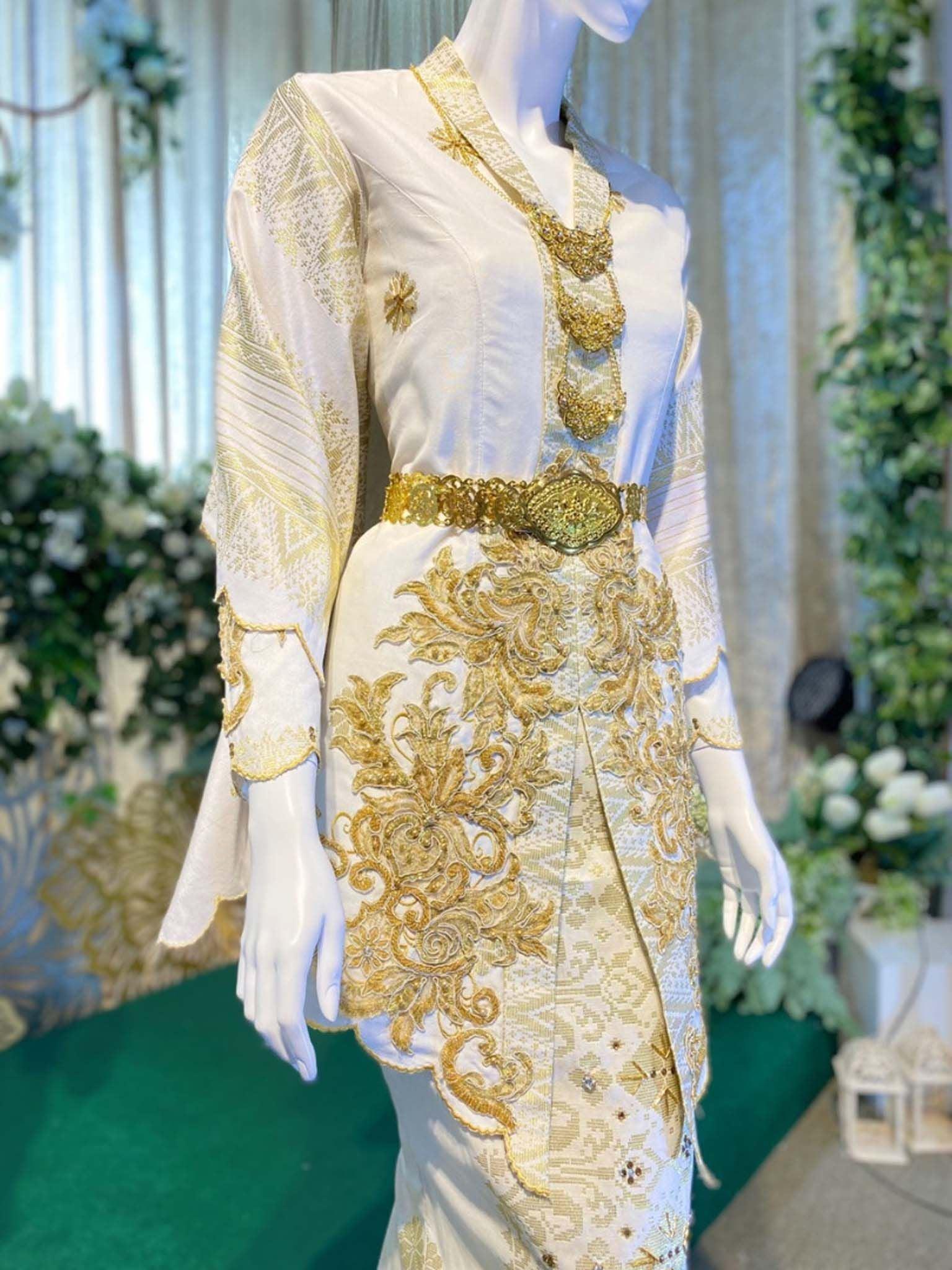 Sepasang baju pengantin, baju Kebaya songket berwarna putih dan emas yang dihias menggunakan teknik tambour dan sulaman tangan lengkap aksesori buatan Butik Pengantin PP Signature-A pair of wedding dresses, Kebaya Dress in off-white and gold complete songket embellished using tambour technique and hand embroidery complete with accessories made by PP Signature Bridal Boutique